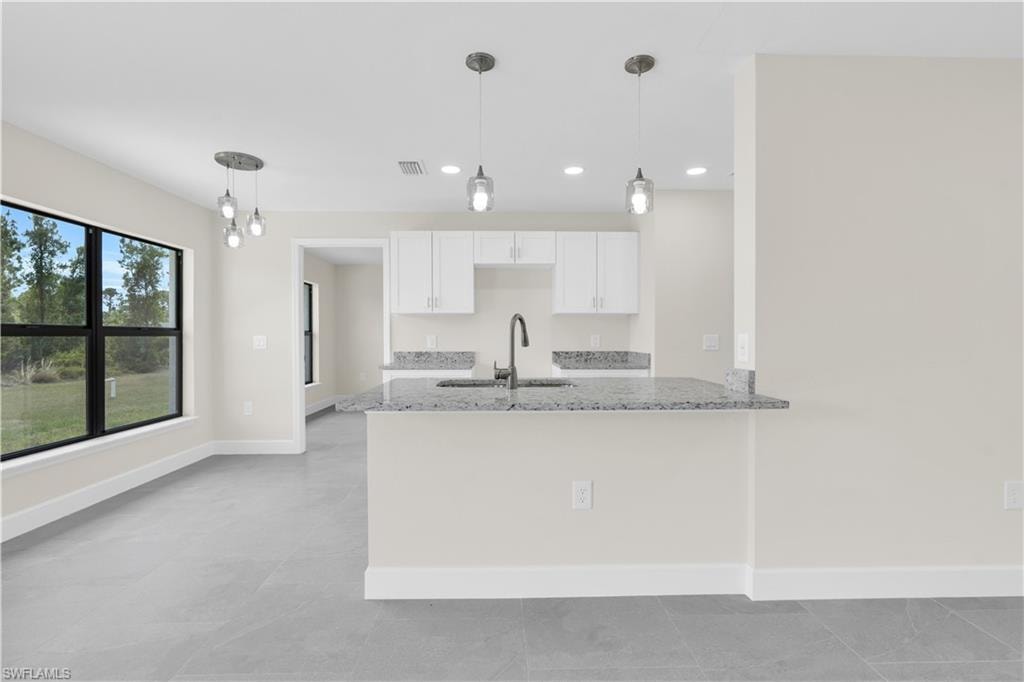 Well-appointed kitchen featuring white cabinetry, a large sink, and granite countertops