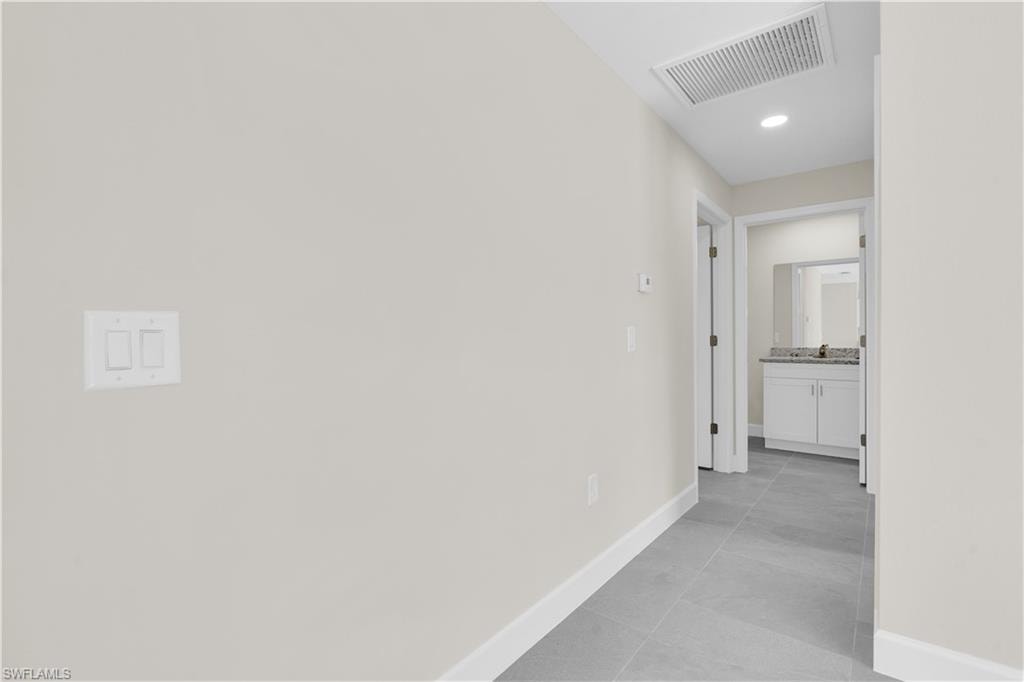 Hallway featuring recessed lighting, tile flooring, and a bathroom vanity with a countertop and mirror