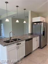 Kitchen island with a double basin sink, stainless steel faucet, white shaker-style cabinetry, and granite countertops