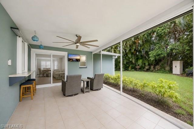 Screened patio with large format tile flooring, ceiling fan, and a built-in bar