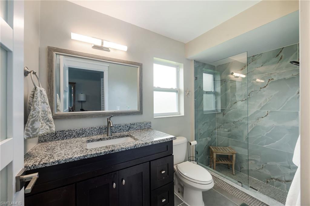 Spacious bathroom featuring a dark wood vanity with a granite countertop, a rectangular undermount sink, and a framed mirror