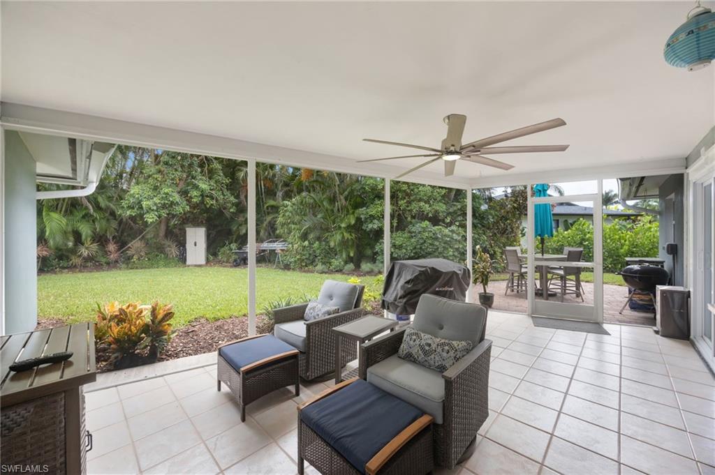 Screened patio with tiled flooring, a ceiling fan, and a view of the manicured lawn