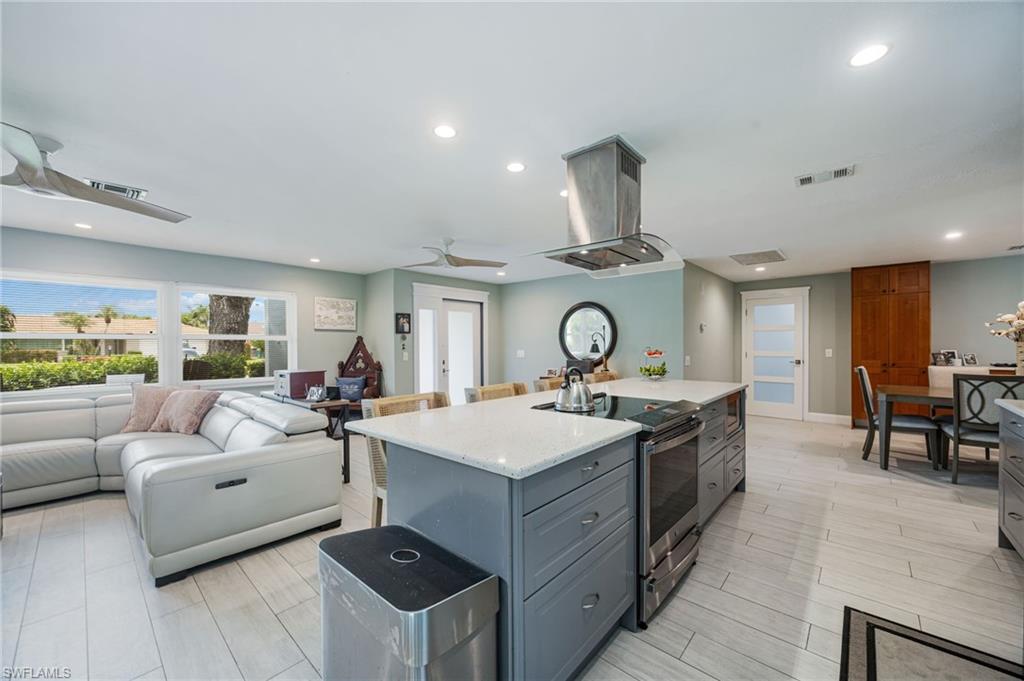 Kitchen featuring a central island with an integrated cooktop, stainless steel range hood, and light-toned countertops
