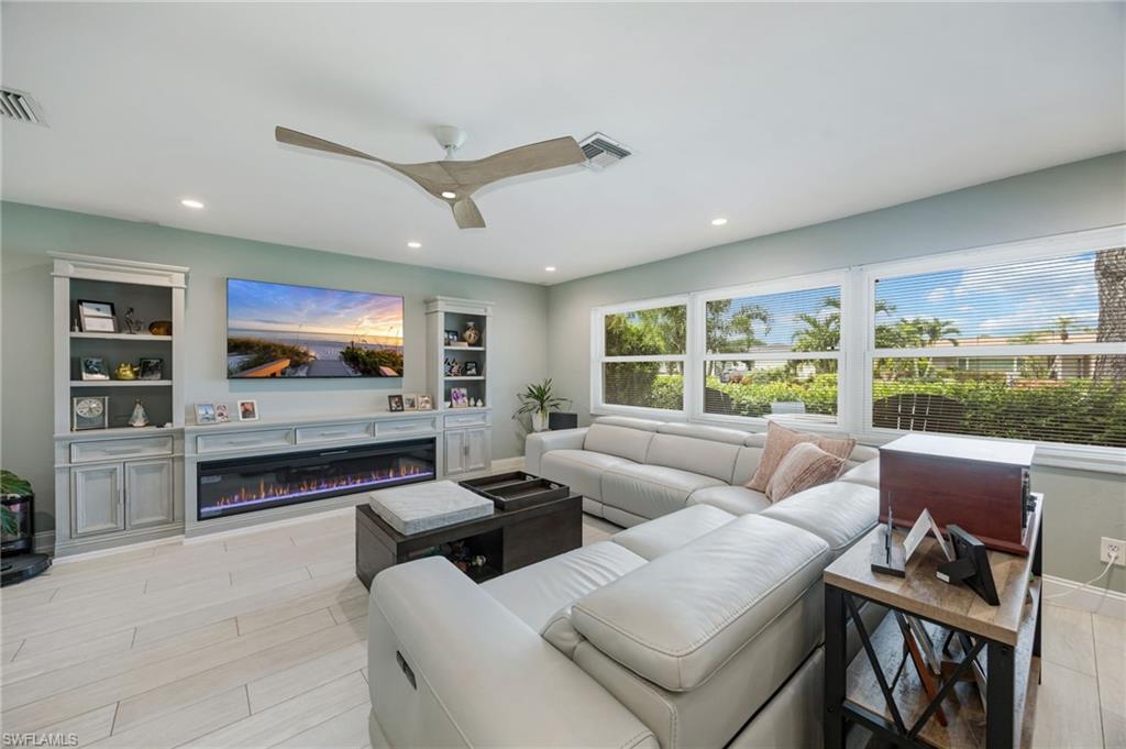 Recessed lighting throughout, built-in entertainment center with fireplace, ceiling fan, multiple windows with blinds, and tile flooring