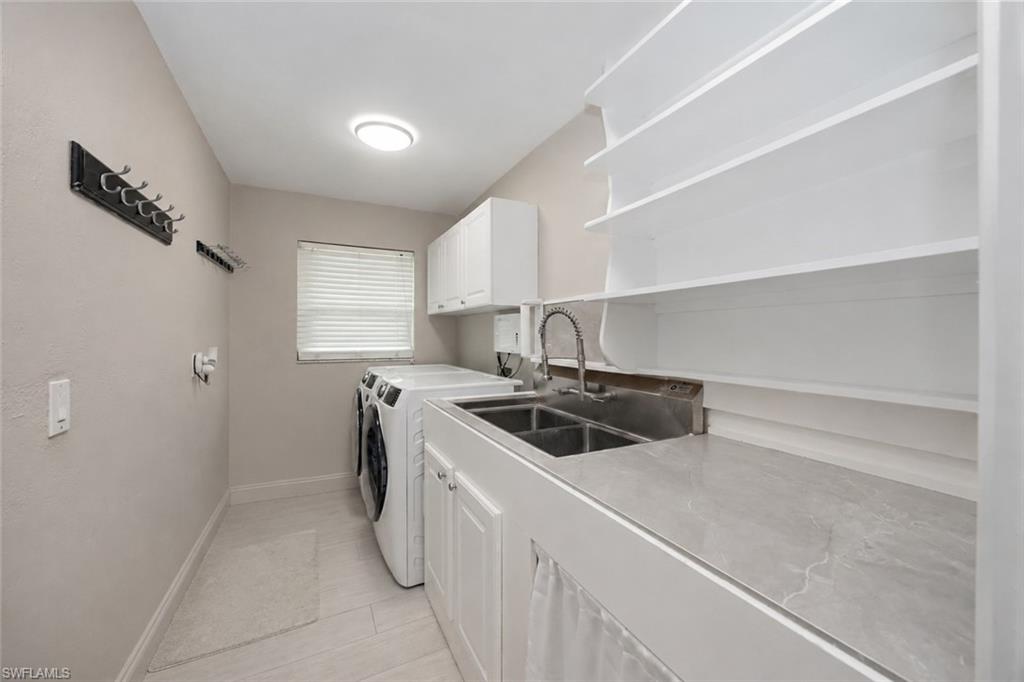 Laundry area featuring a dual basin sink, white cabinetry, open shelving, and a window with blinds