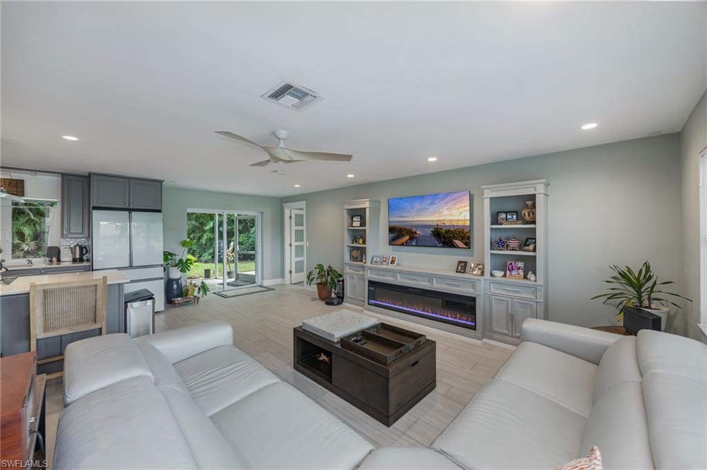 Recessed lighting, wood-finish flooring, ceiling fan, sliding glass doors, and built-in cabinetry with integrated electric fireplace