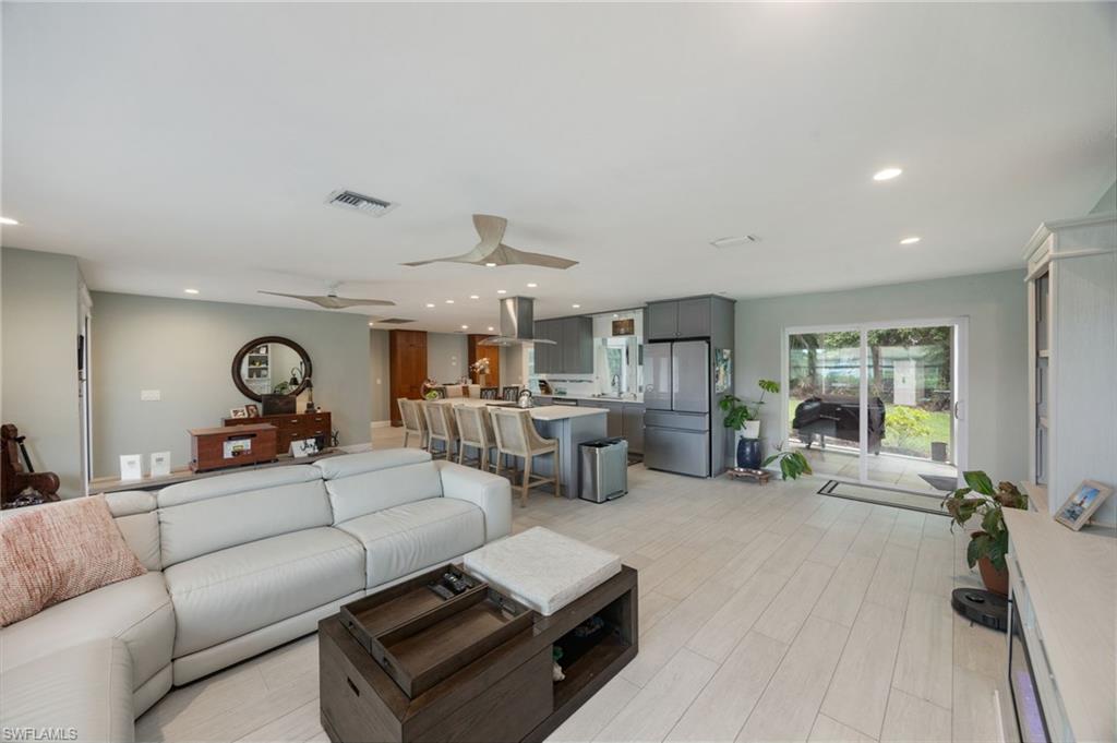 Open concept living area with light-toned wood-finish flooring, recessed lighting, and ceiling fans