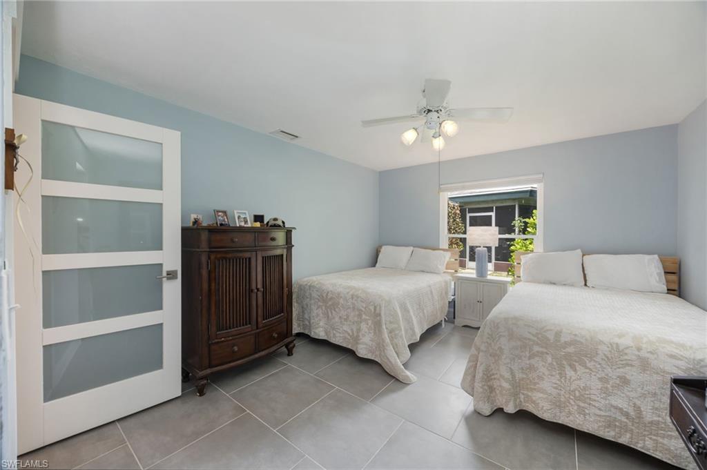 Room featuring tile flooring, a ceiling fan with integrated lighting, and a window with exterior views