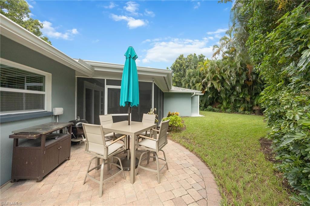Expansive backyard featuring a paver patio, screened enclosure, and lush perimeter landscaping