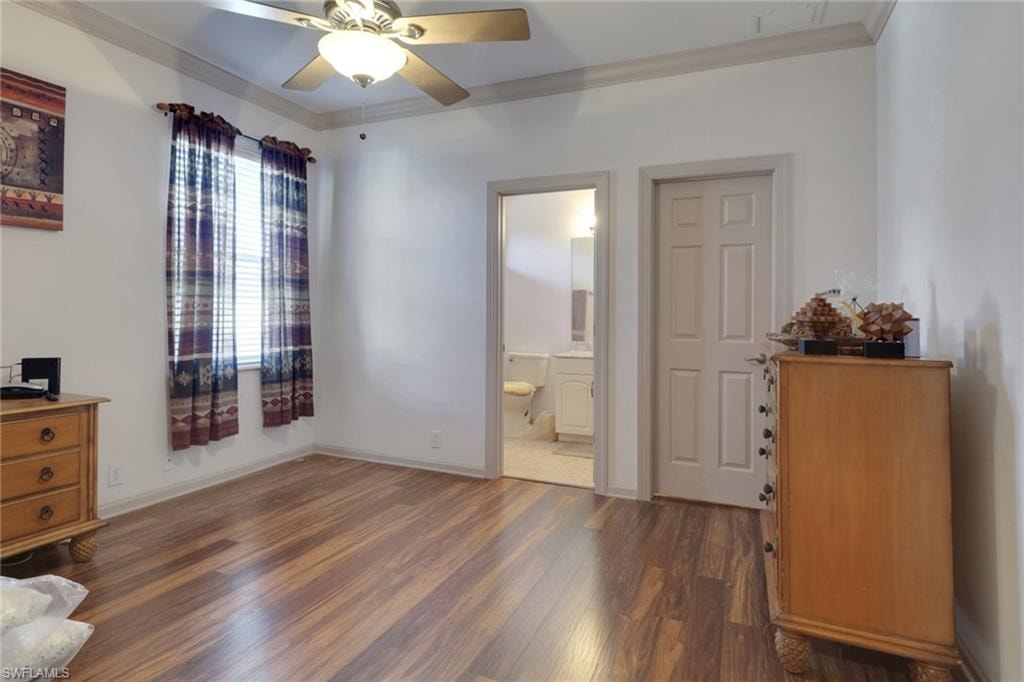 Bedroom featuring crown molding, dark wood-style flooring, ceiling fan, and ensuite bath
