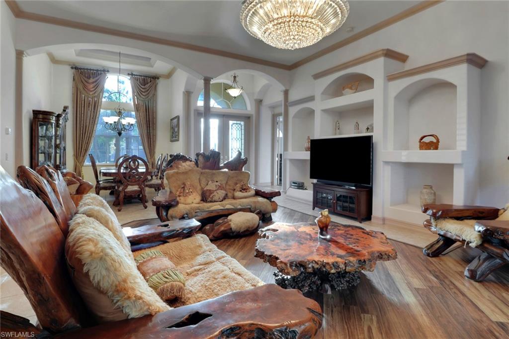 Living area featuring a chandelier, built in features, crown molding, and plenty of natural light