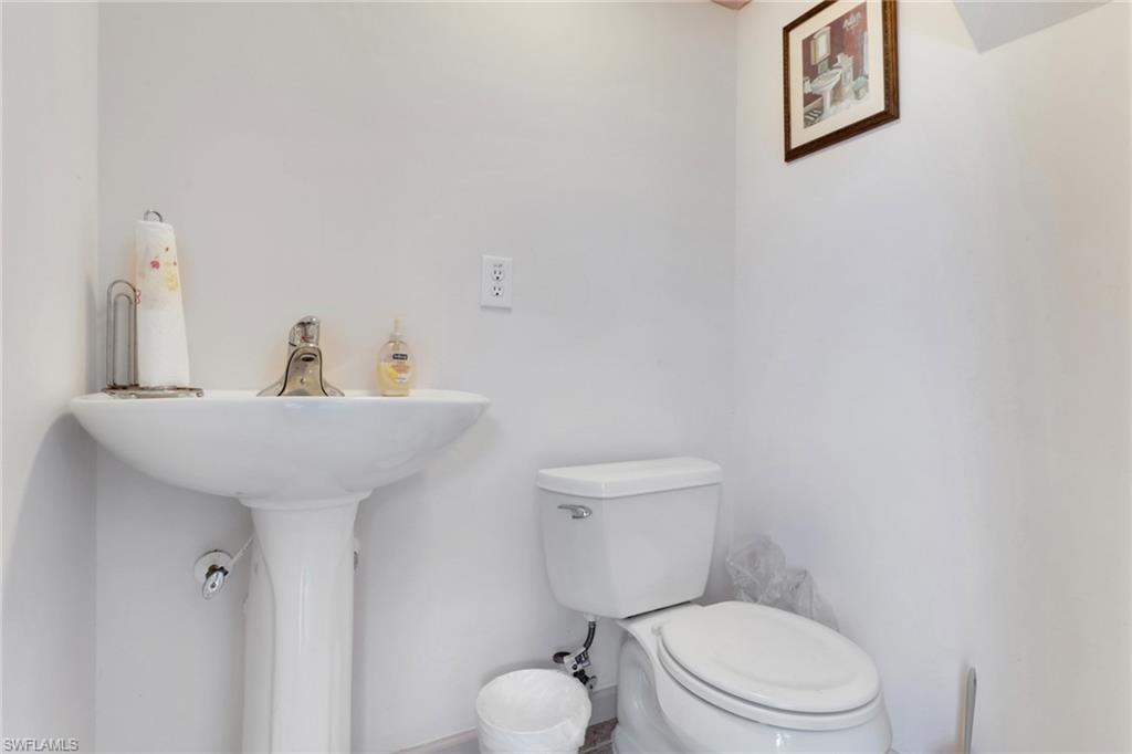 Half bathroom featuring toilet and a sink in pool area