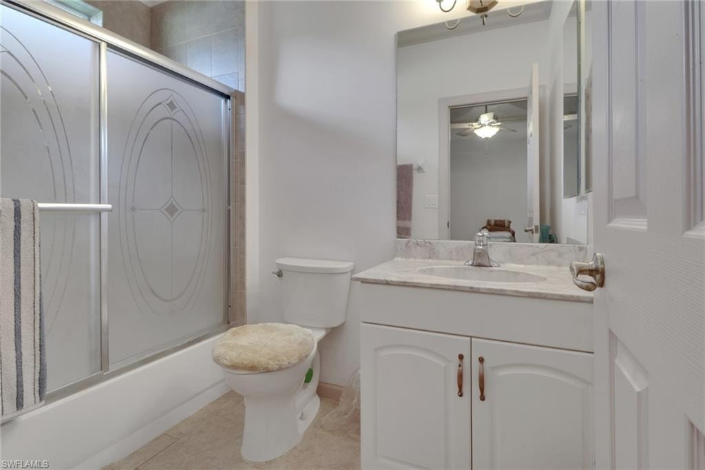 Full bath featuring shower / bath combination with glass door, vanity, light tile patterned floors, and a ceiling fan