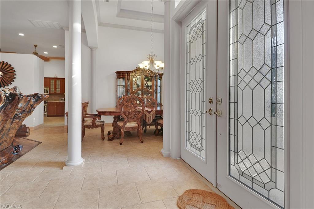Entrance foyer with decorative columns, a chandelier, light tile patterned floors, and recessed lighting