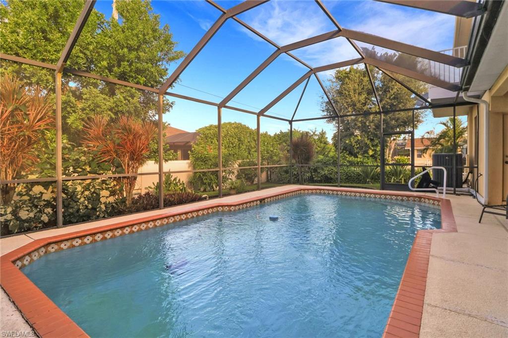 Outdoor pool featuring glass enclosure, a sunroom, and a patio area