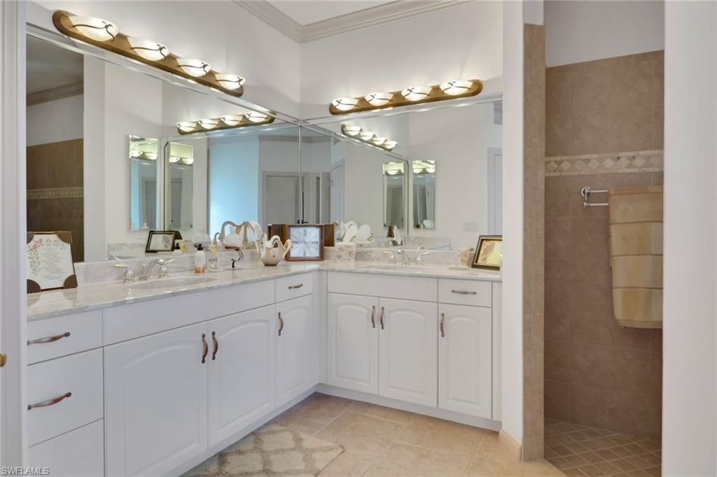 Full bath with double vanity, a walk in shower, ornamental molding, and light tile patterned floors