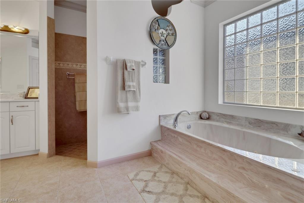 Full bathroom featuring vanity, a bath, a walk in shower, and light tile patterned flooring