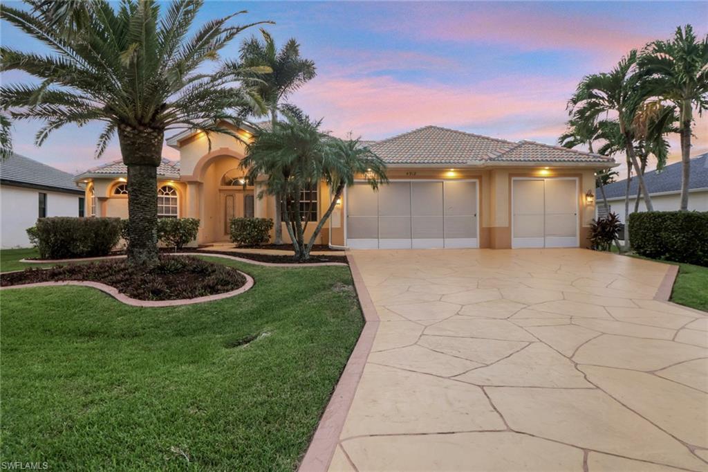 View of front of house featuring a front yard, a tiled roof, stucco siding, and a garage