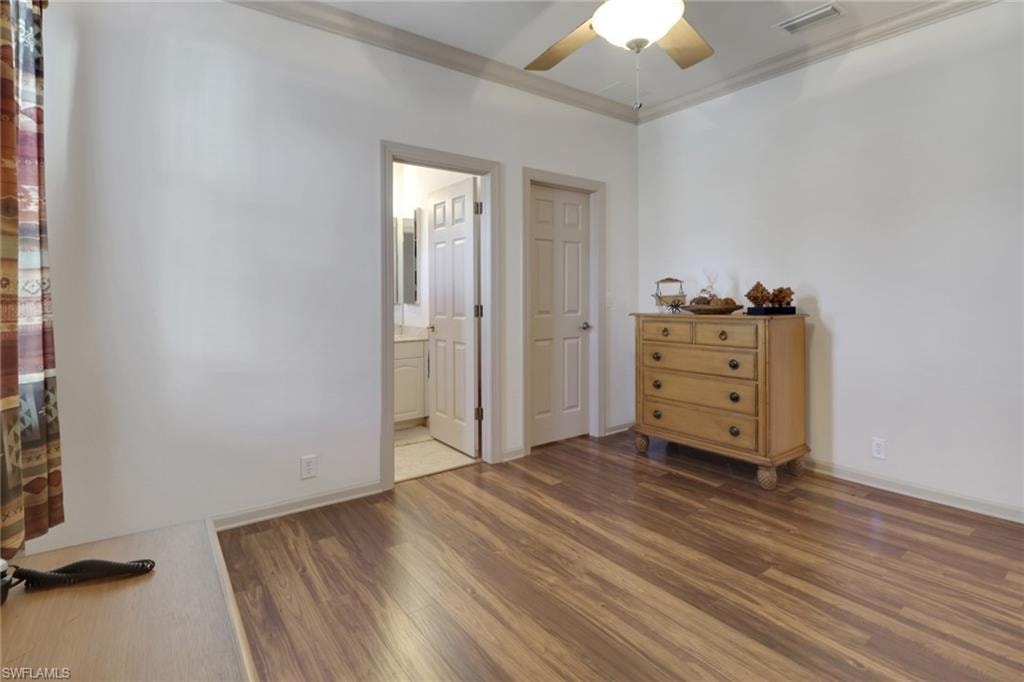 Bedroom with crown molding, dark wood finished floors, and ceiling fan