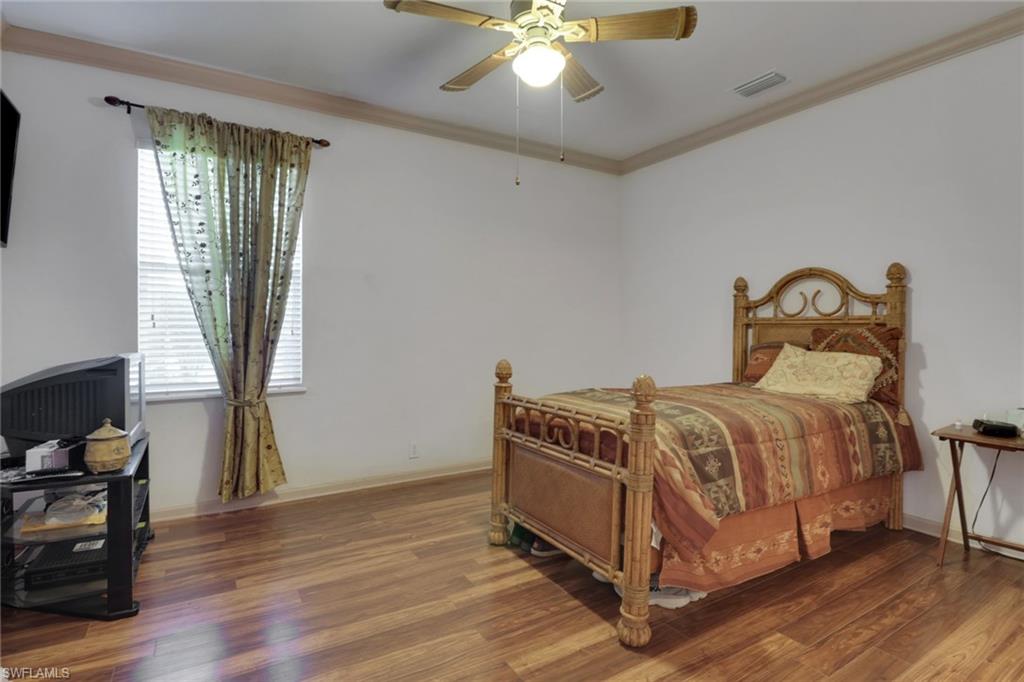 Bedroom featuring crown molding, wood finished floors, and a ceiling fan