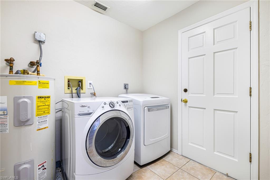 Laundry area featuring a paneled door, tiled flooring, and a water heater