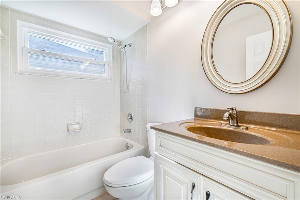 White tiled bathtub with a fixed showerhead and an adjacent toilet