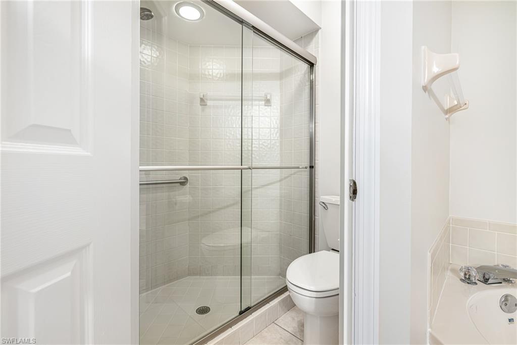 Walk-in shower with clear glass enclosure, integrated seating, and a recessed light fixture