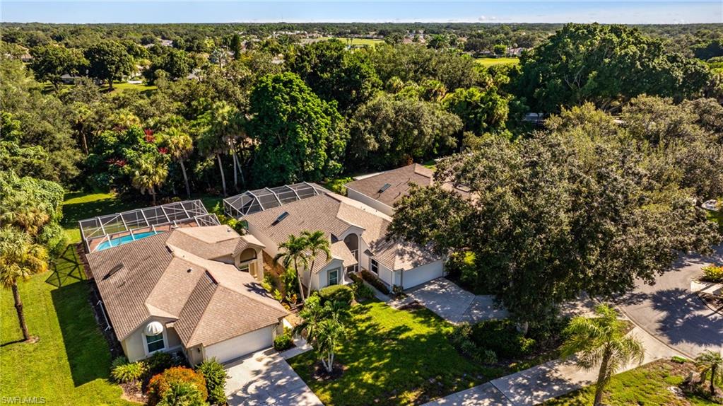 Expansive aerial view showcasing a multi-structure residence with clay tile roofing, situated on substantial grounds featuring mature landscaping, manicured lawn areas, and established trees
