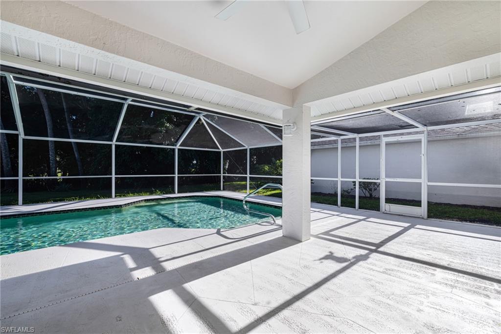 Screened-in pool deck with a rectangular swimming pool, integrated steps, and a handrail