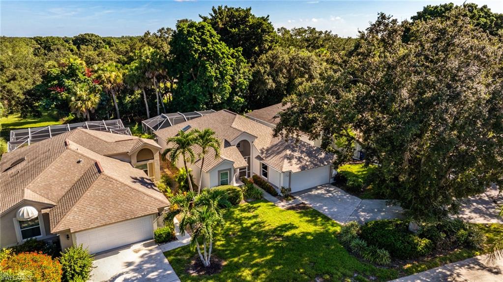 Multiple asphalt shingle roofs, structured screened enclosures, mature landscaping, and an expansive paved driveway