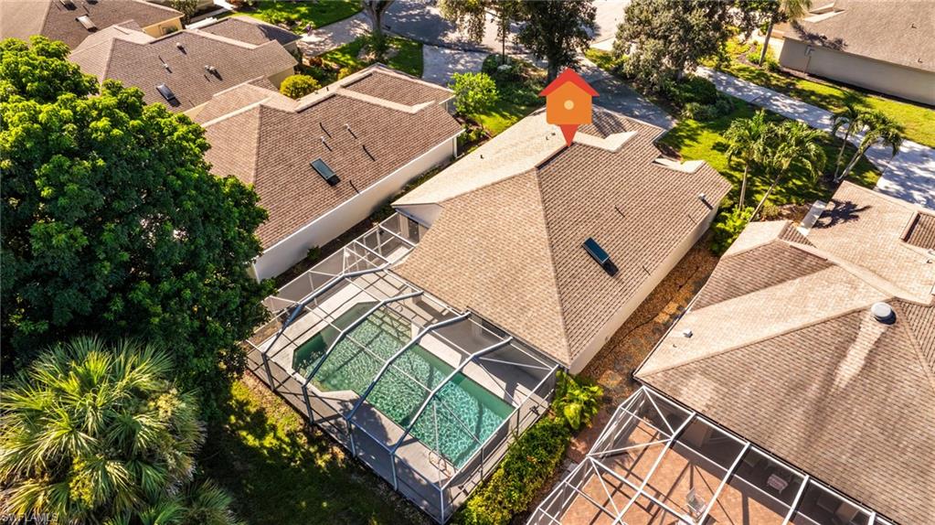 Screened swimming pool with a paved deck, surrounded by mature landscaping and a privacy wall