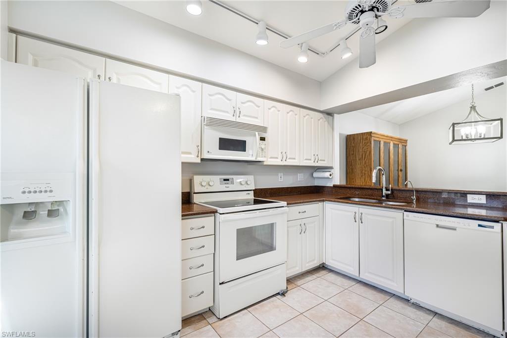 Kitchen featuring white cabinetry, brown countertops, white appliances, and tiled flooring