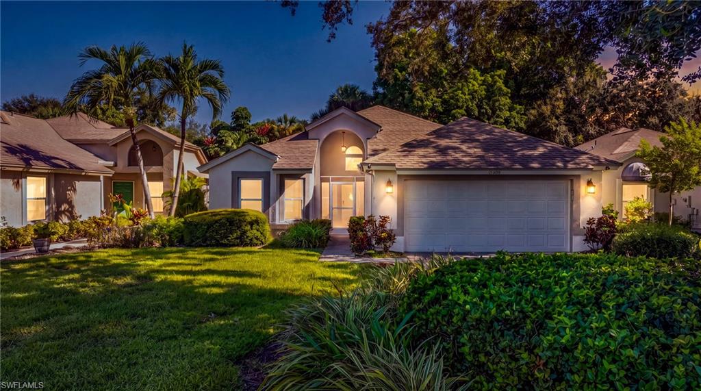 Stucco exterior with an arched entry, attached garage, and mature landscaping