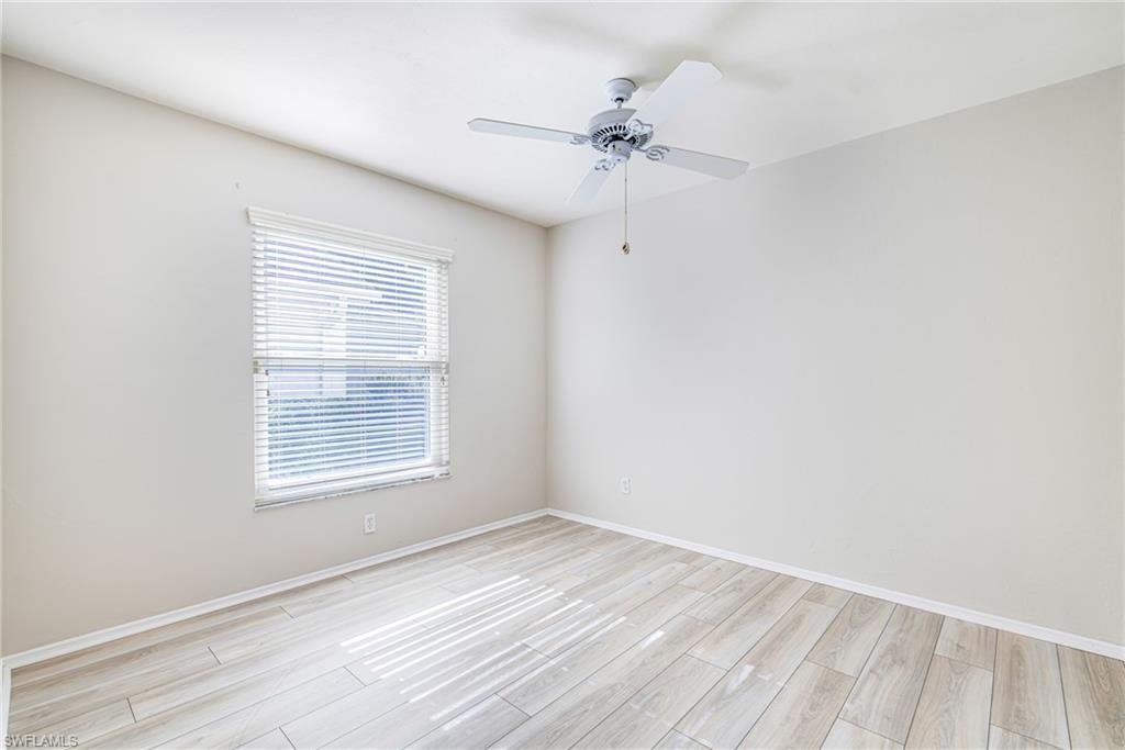 Light wood-finish flooring, white walls, and a ceiling fan with light fixture