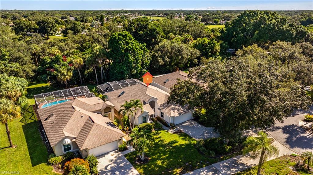 Tile roof residence with a screened pool enclosure, mature landscaping, and an attached garage