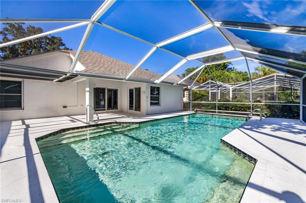 Screened-in pool enclosure featuring a concrete deck, built-in pool steps, and clear blue water