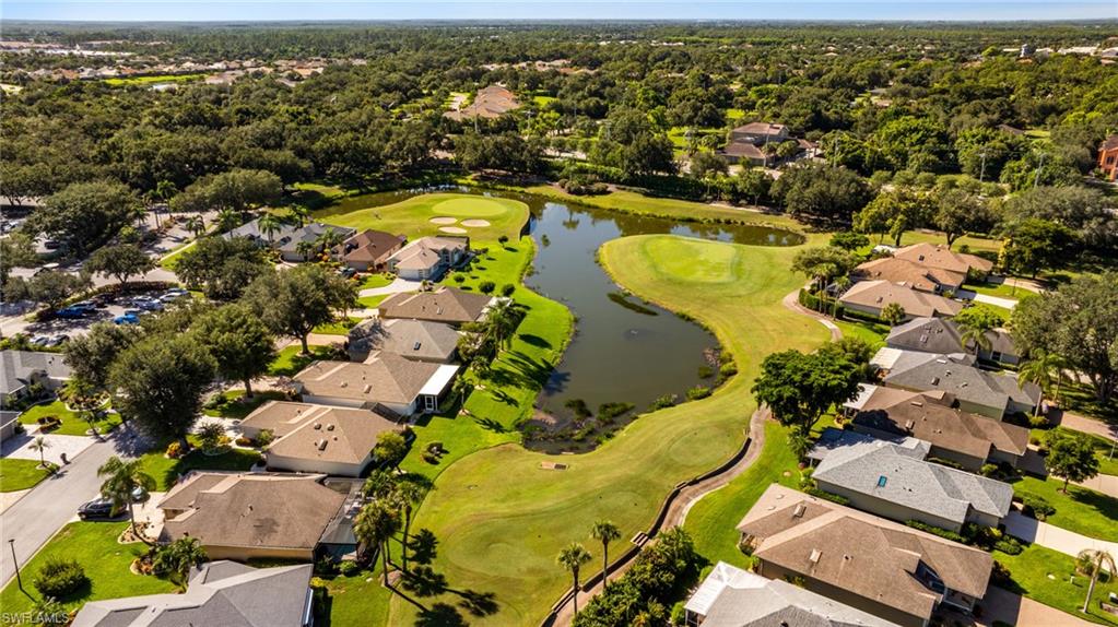 Aerial perspective showcasing a residential community with mature landscaping, adjacent to a golf course and a pond