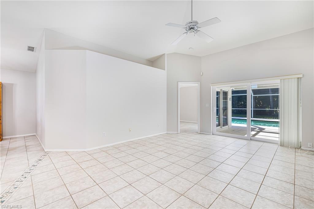 Vaulted ceilings, a ceiling fan, and white tile flooring with decorative inlay