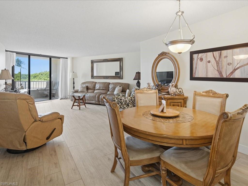 Open-concept living space with wood-finish flooring, a contemporary ceiling light fixture, and floor-to-ceiling glass doors leading to a private balcony with a metal railing