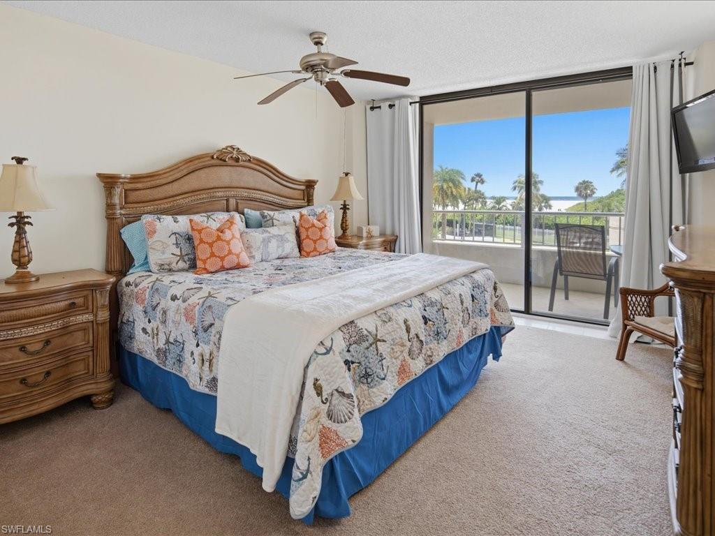 Carpeted room with a ceiling fan, a large sliding glass door, and a private balcony featuring a metal railing