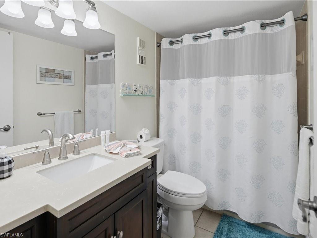 Vanity with a white countertop and undermount sink, brushed nickel faucet, large wall mirror, and built-in lighting fixture