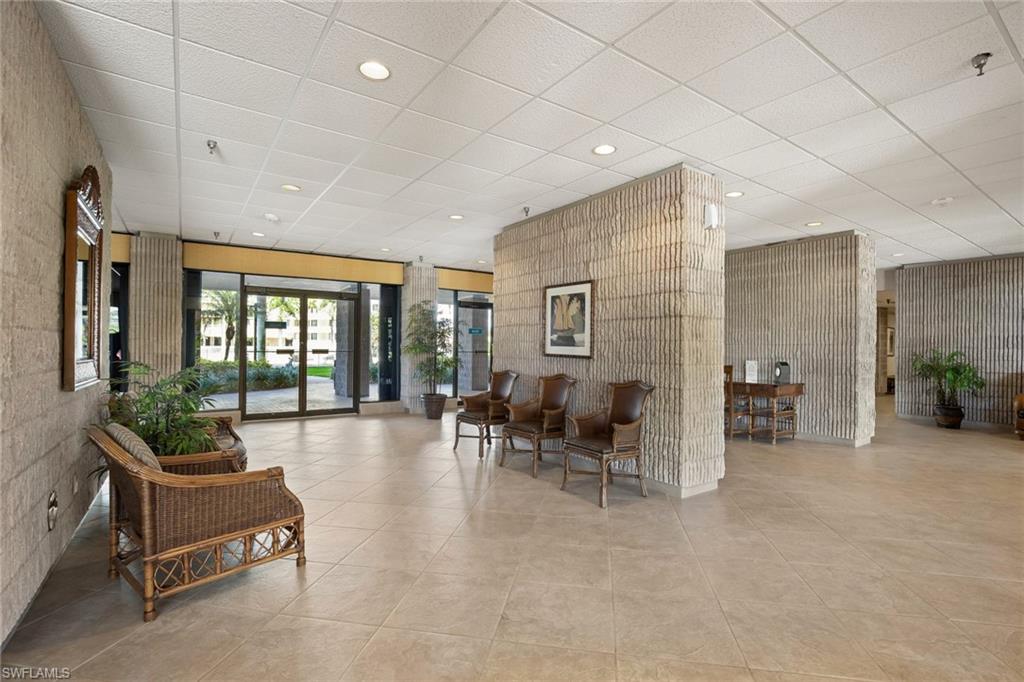 Spacious lobby featuring tile flooring, textured accent walls, recessed lighting, and glass entry doors