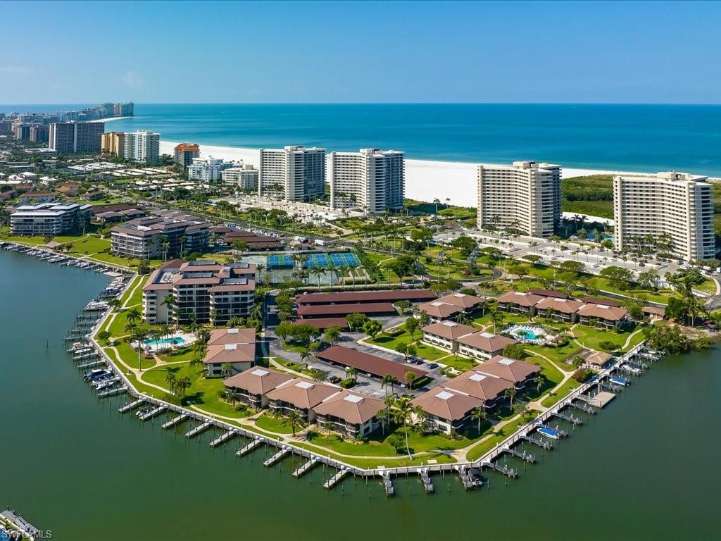 Coastal community featuring waterfront properties, private boat docks, multiple swimming pools, lush landscaping, and tennis courts