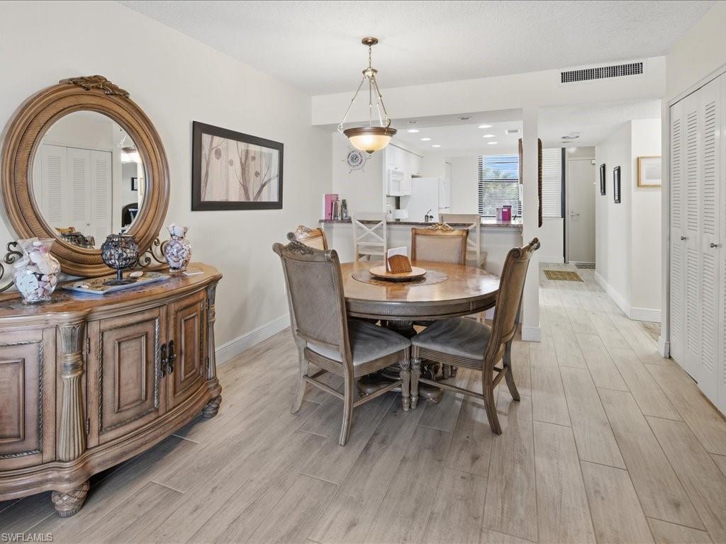 Open concept layout with wood-finish flooring, a built-in kitchen pass-through, and louvered bifold closet doors