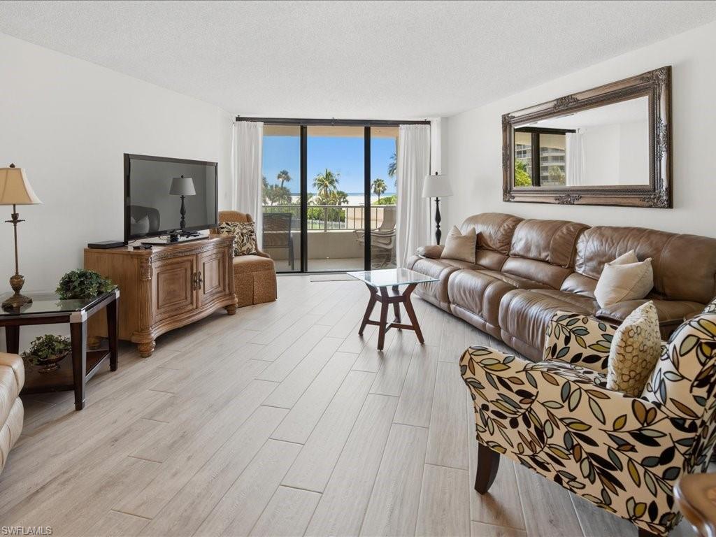 Sliding glass doors opening to a balcony, light wood-finish flooring, and a large ornate wall mirror