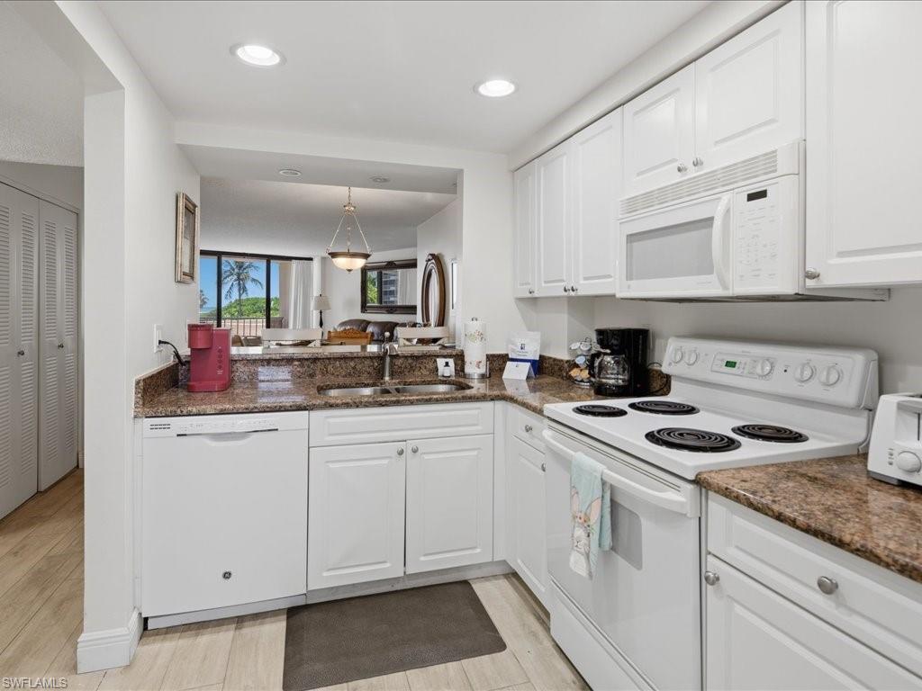 Kitchen featuring white cabinetry, brown granite-style countertops, white appliances, and recessed lighting