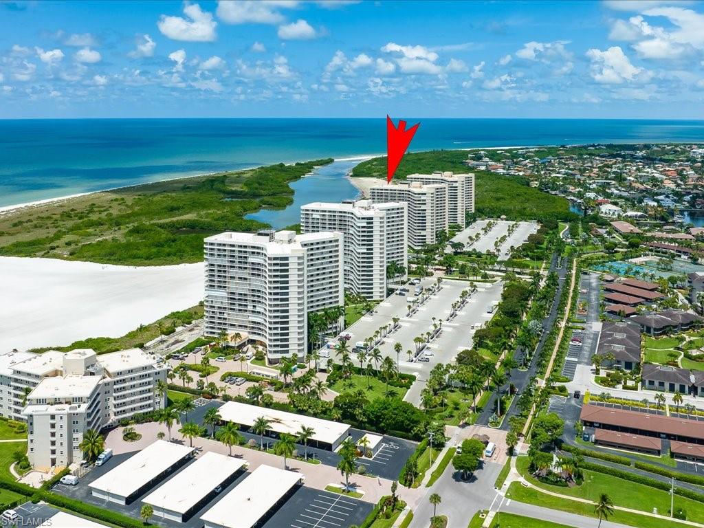 Coastal high-rise building with a white sand beach, ocean, and lush natural landscaping