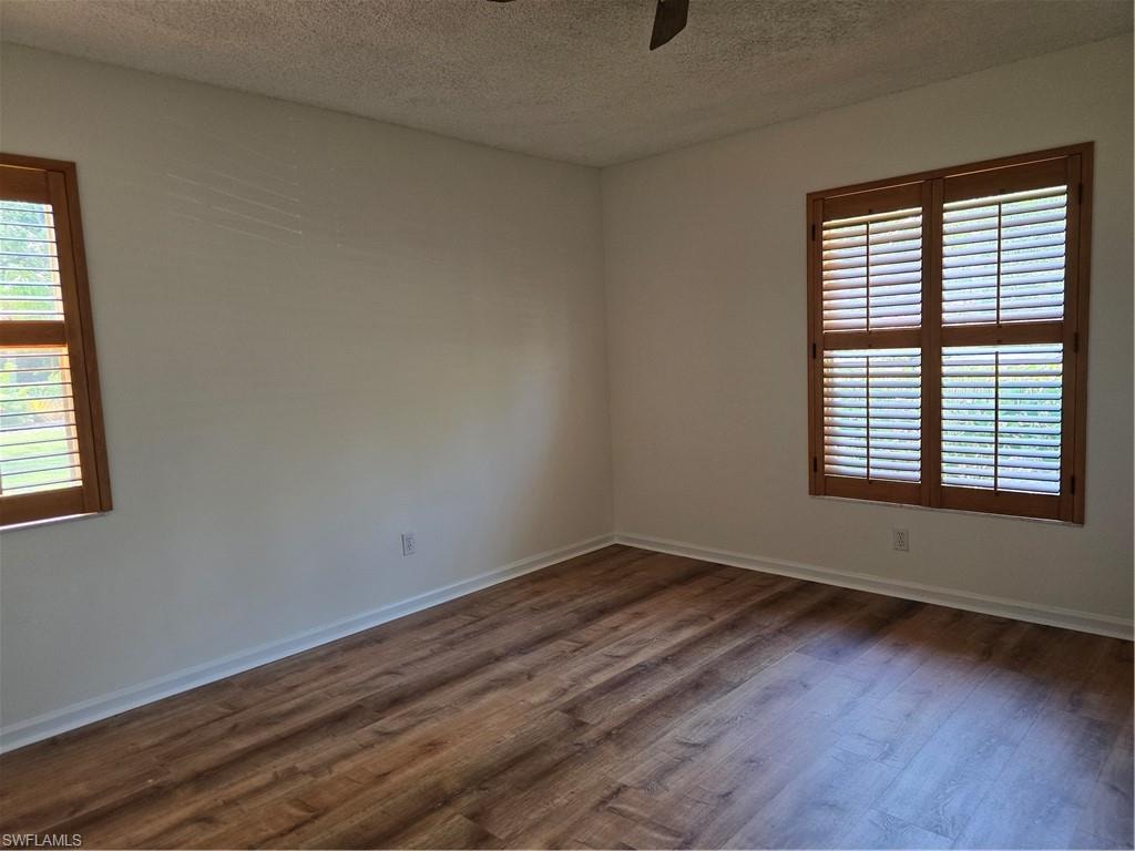Wood-finish flooring throughout master bedroom, complemented by light-toned walls and dual windows featuring wood plantation shutters