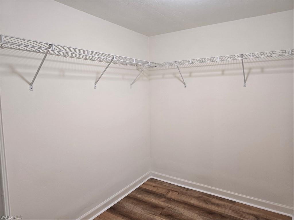Walk-in closet with white wire shelving and wood-finish flooring