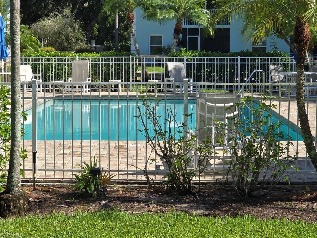 Community in-ground pool with surrounding paver decking and palm trees
